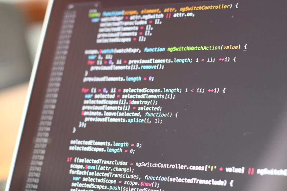 In the foreground, a computer screen displays lines of programming code with syntax highlighting in colors such as blue, orange, green, and red, set against a dark background. The code includes variou